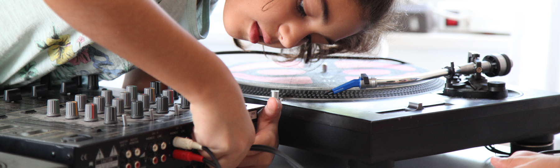 Jugendlicher*r verkabelt ein Mischpult
